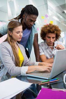 Creative young business people using laptop at office desk