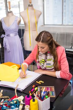 Attractive female fashion designer sketching dress