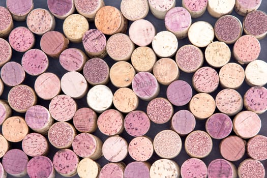 Old wine corks arranged in a background pattern viewed from above with both red and white wine represented in a random scatter, full frame