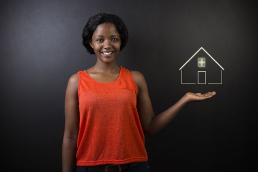 South African or African American woman teacher, student, saleswoman or businesswoman against black background holding house, home or real estate