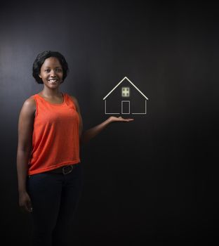 South African or African American woman teacher, student, saleswoman or businesswoman against black background holding house, home or real estate