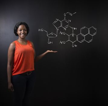 Learn science or chemistry formula confident beautiful South African or African American woman teacher or student chalk blackboard background