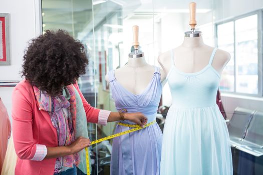 Female fashion designer measuring dummy waist