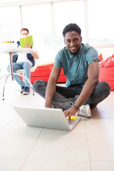 Portrait of smiling young man using laptop on floor