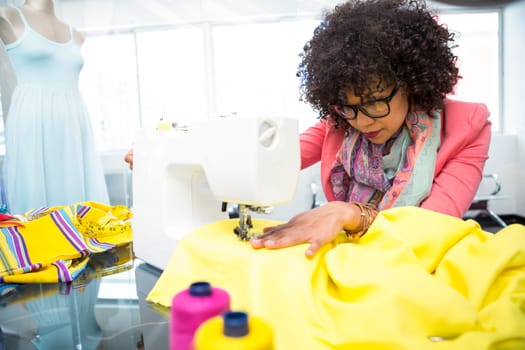 Attractive female fashion designer using sewing machine