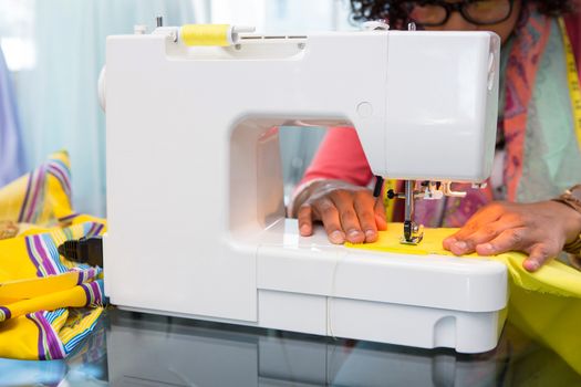 Mid section of female fashion designer using sewing machine