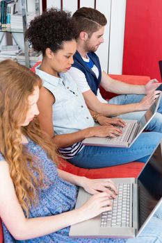 Creative team using laptops on sofa in office