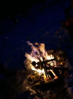 Night fire with sparks in a forest in winter                               