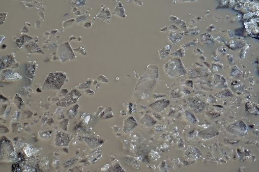 Shattered ice on gray water as a background                               