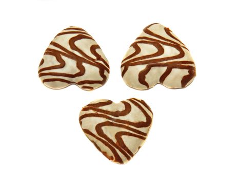Three heart-shaped cookies covered with white icing and chocolate pattern isolated
