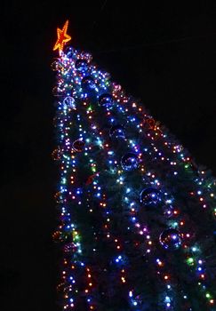 Christmas tree decorated with colorful bright lights cropped diagonally                               