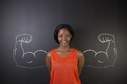South African or African American woman teacher with healthy strong arm muscles for success on blackboard background