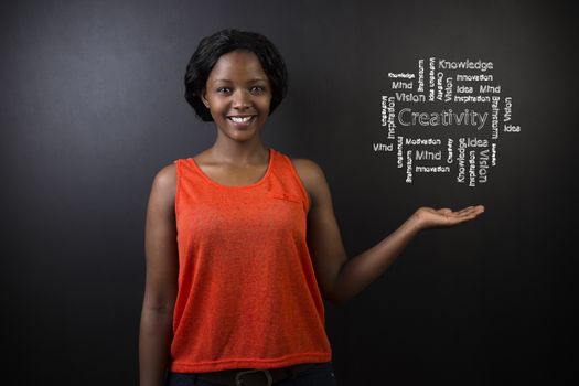 South African or African American woman teacher or student with her hand out displaying a chalk creativity diagram against a chalk blackboard background