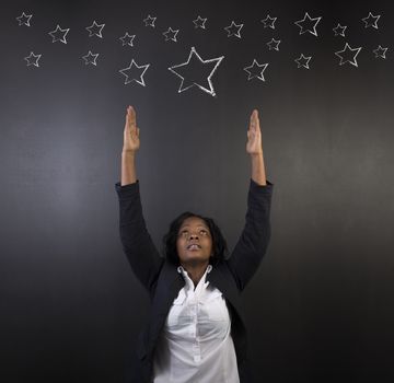 South African or African American woman teacher or student reaching for the stars chalk success diagram against chalk blackboard background