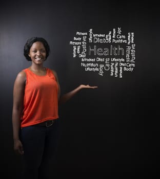 South African or African American woman teacher or student standing with her hand out against a chalk blackboard background with a chalk health diagram