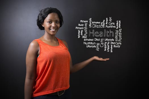 South African or African American woman teacher or student standing with her hand out against a blackboard background with a chalk health diagram