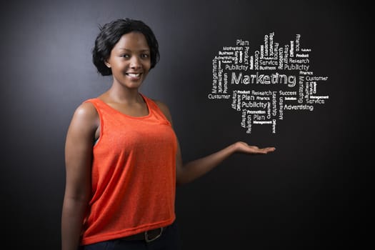 South African or African American woman teacher or student with her hand out standing against a blackboard background with a chalk marketing diagram