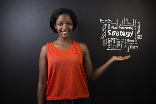 South African or African American woman teacher or student holding hand out against a blackboard background with a chalk strategy diagram