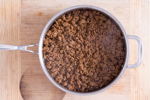 Close up Big Pan with Smoking Hot Ground Beef on Top of a Wooden Cutting Board, Captured in High Angle View.