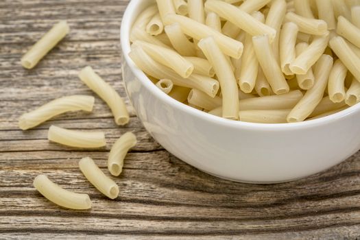 healthy, gluten free quinoa pasta (macaroni)  - small ceramic bowls against grained wood