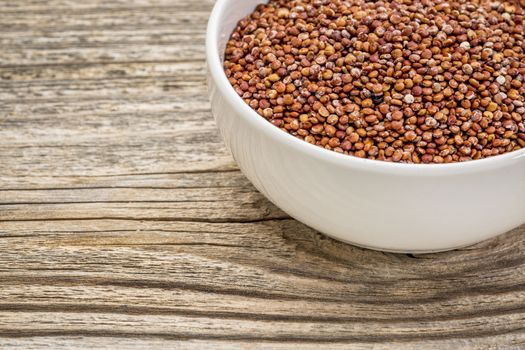 gluten free, red quinoa grain in a small, ceramic bowl against grained wood