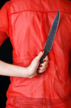 A woman conceals a kitchen knife for an unforseen attack on possible home invaders.