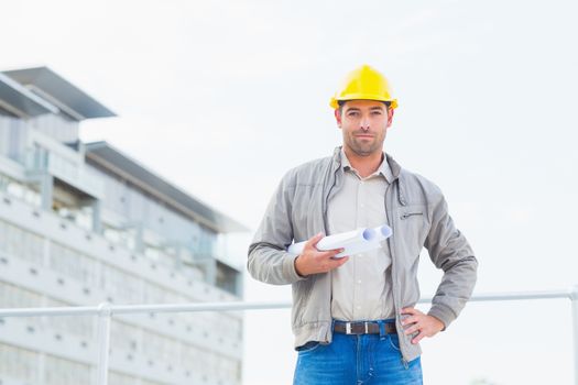 Portrait of confident male architect with blueprints outdoors