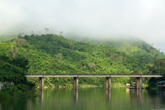 Bridge across river with mountain and fog
