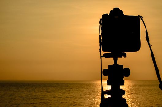 Silhouette of DSLR camera with sea at sunrise, Photo at morning time concept