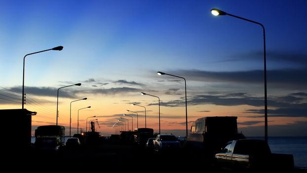 Silhouette of car parking on the bridge with sunset sky and sea background