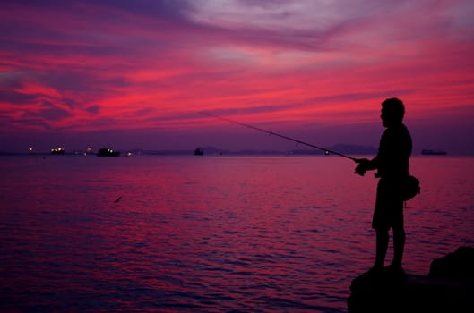 Silhouette of fishing man beside the sea