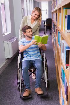 Smiling disabled student with classmate in library at the university