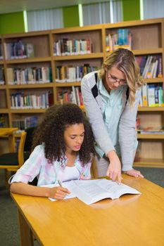 Student getting help from tutor in library at the university