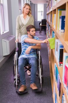 Smiling disabled student with classmate in library at the university