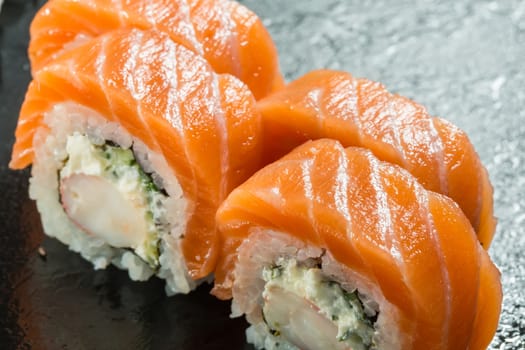 Salmon and caviar rolls served on a black plate