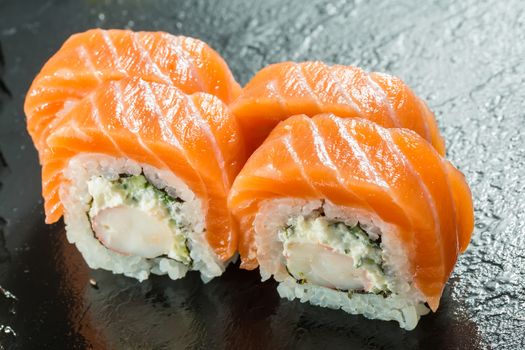 Salmon and caviar rolls served on a black plate