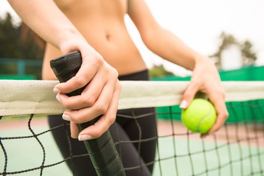 young woman with yellow ball and racket near net