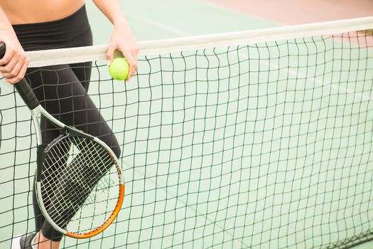 young woman with yellow ball and racket near net