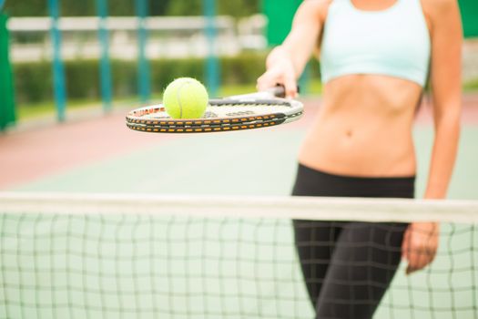 young woman with yellow ball and racket near net