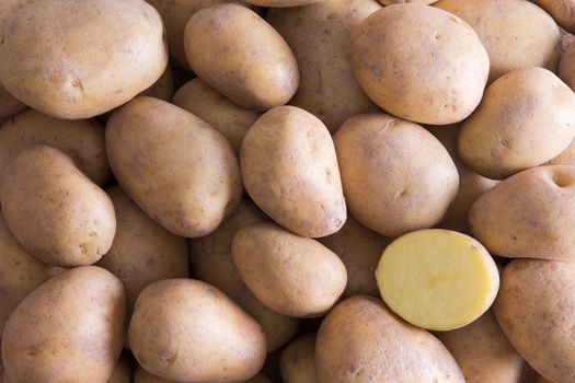 Full Frame Background of Whole Golden Potatoes with One Cut Half Section in Lower Right Corner