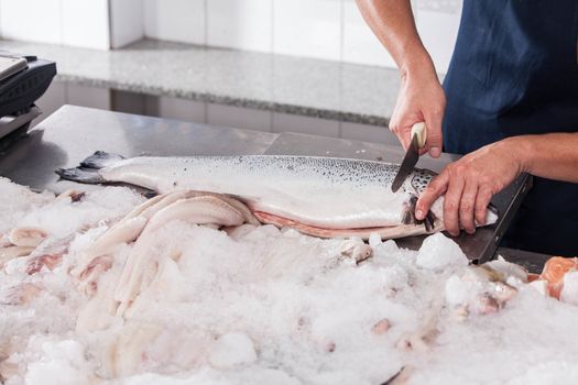 Man cutting a pink salmon on the table