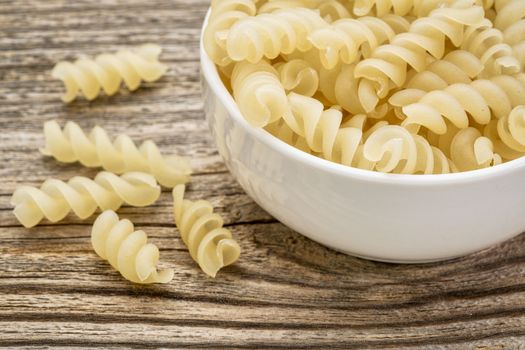 healthy, gluten free quinoa pasta (fusilli)  - small ceramic bowls against grained wood