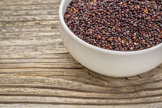 gluten free, black quinoa grain in a small, ceramic bowl against grained wood