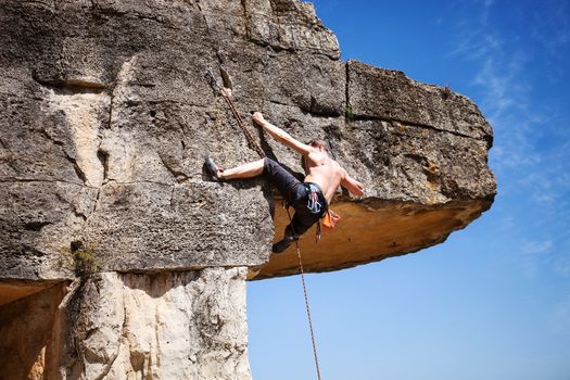 Young male rock climber on challenging route on cliff