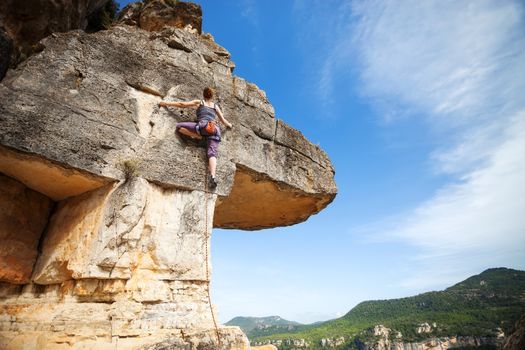 Woman climber on challenging route on cliff