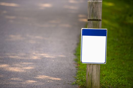 Blank signboard on green grass in park to place your logo or advertising on it