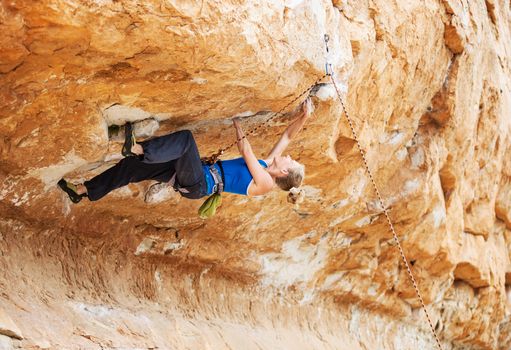 Young female rock climber struggling to make next movement up