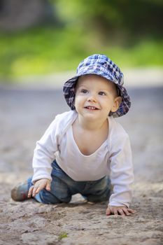 Cute little boy looking up and smiling while crawling on stone paved sidewalk