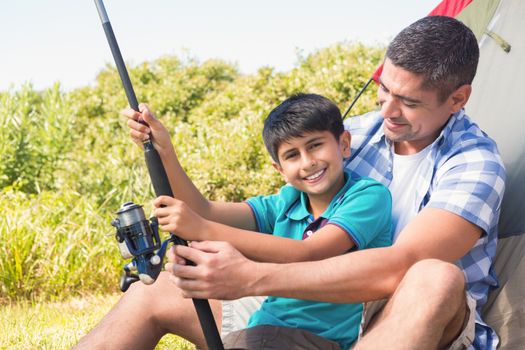 Father and son beside their tent on a sunny day