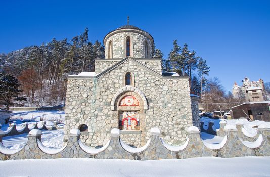 Religious painting on facade of the Templar Church in Bran with Bran Castle on background, Romania